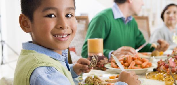 Family eating dinner and a well dressed little boy looking at the camera