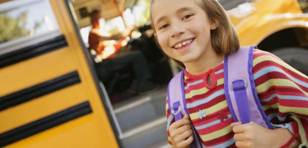 little girl with a backpack getting off a bus