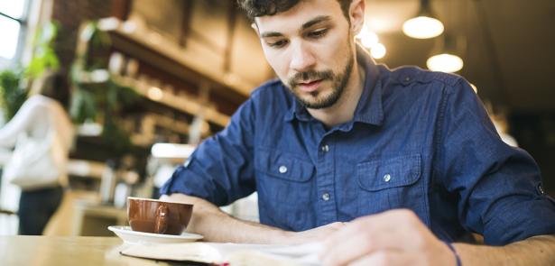 man reading Bible in coffee shop