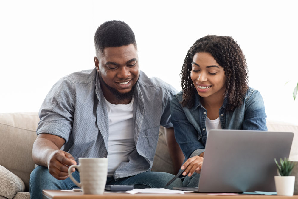 A couple sitting down planing a checklist of what to ask when seeking a provider in front of a laptop.