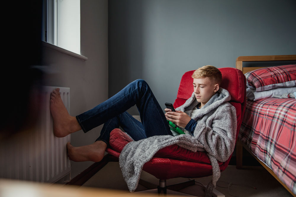 teen in a bedroom on his phone