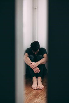 an adult male sitting in a corner